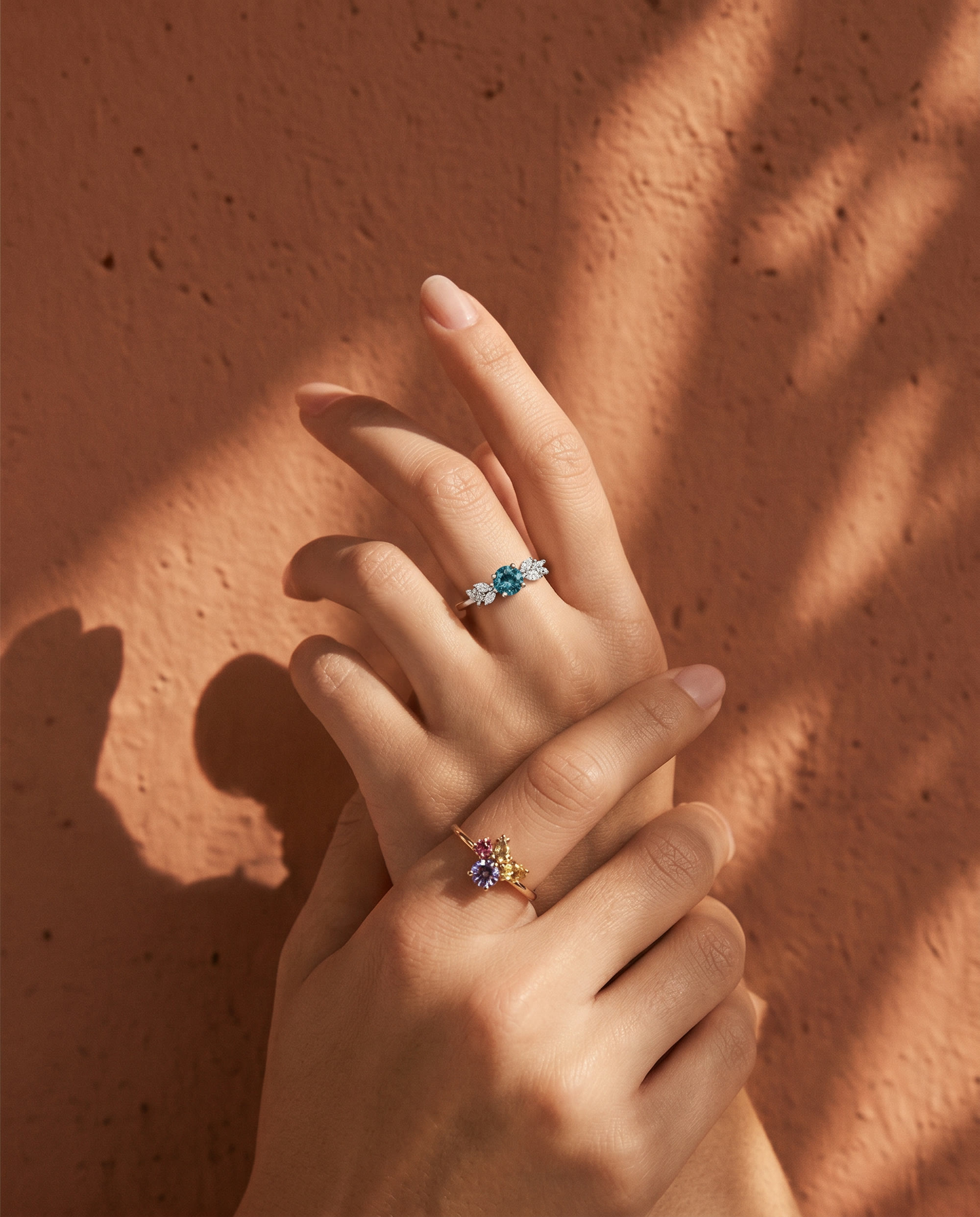 Hands with rings casting shadows on a terracotta wall