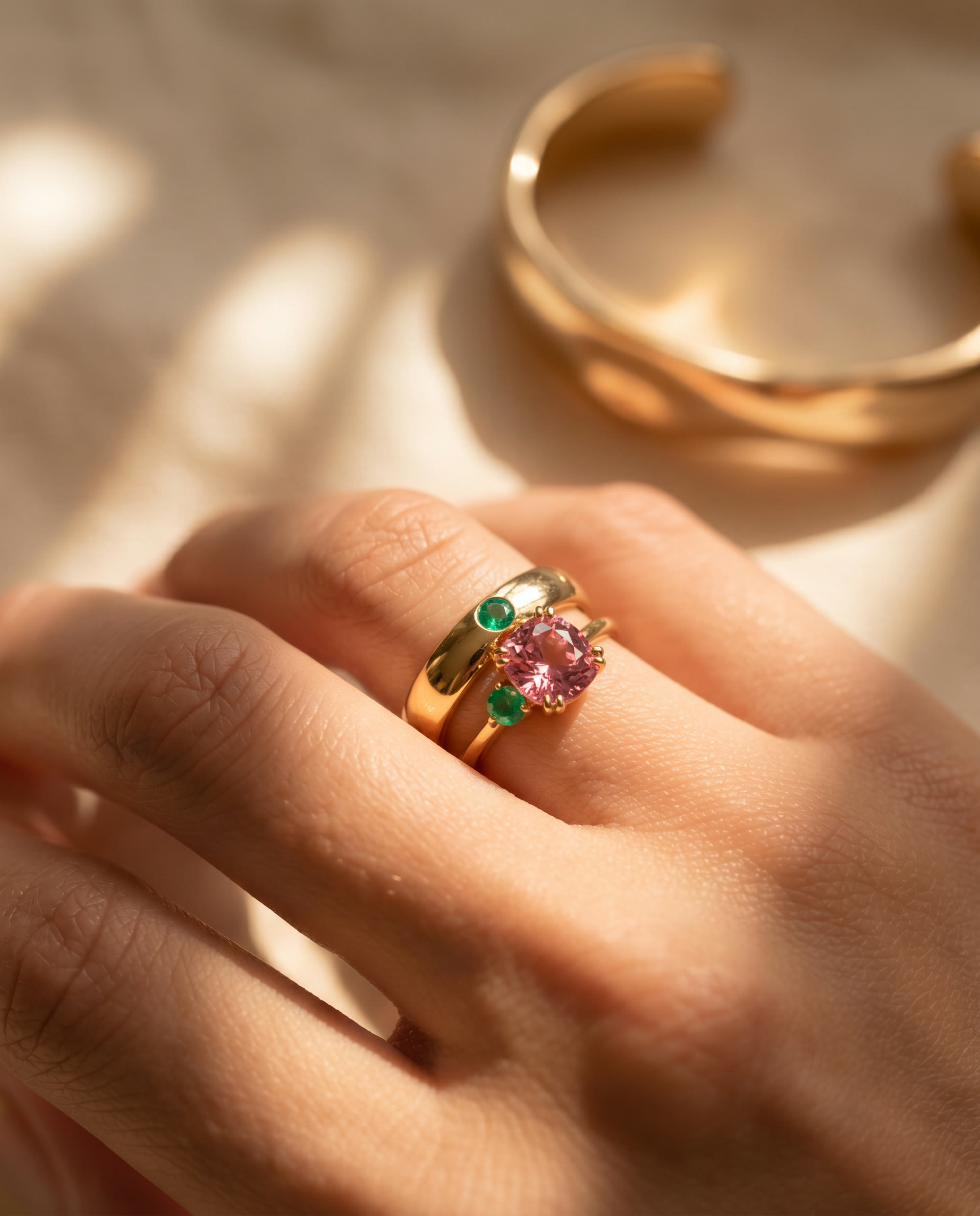 Gold cuff and stacked gem rings in dappled light