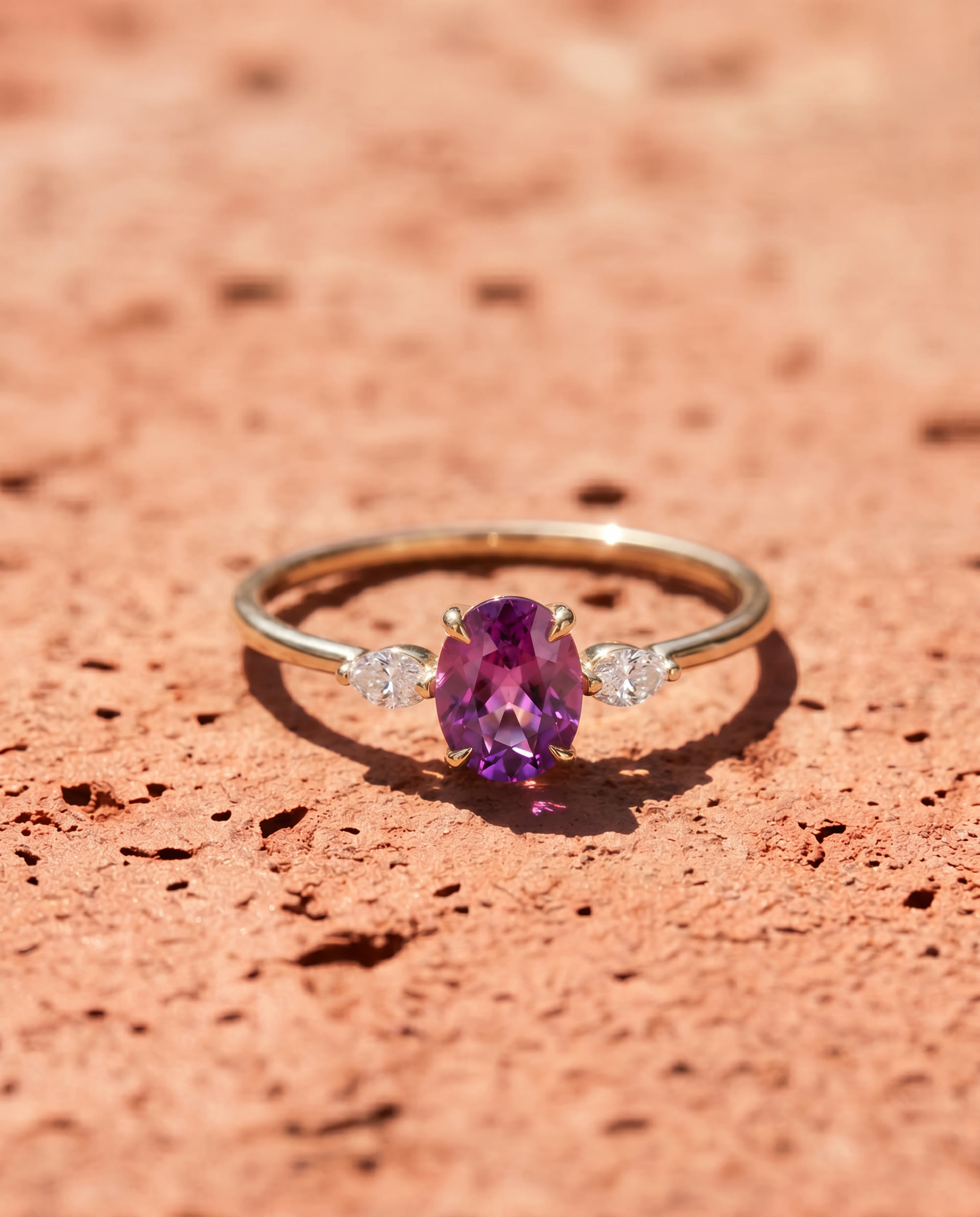 An amethyst ring resting on red sand